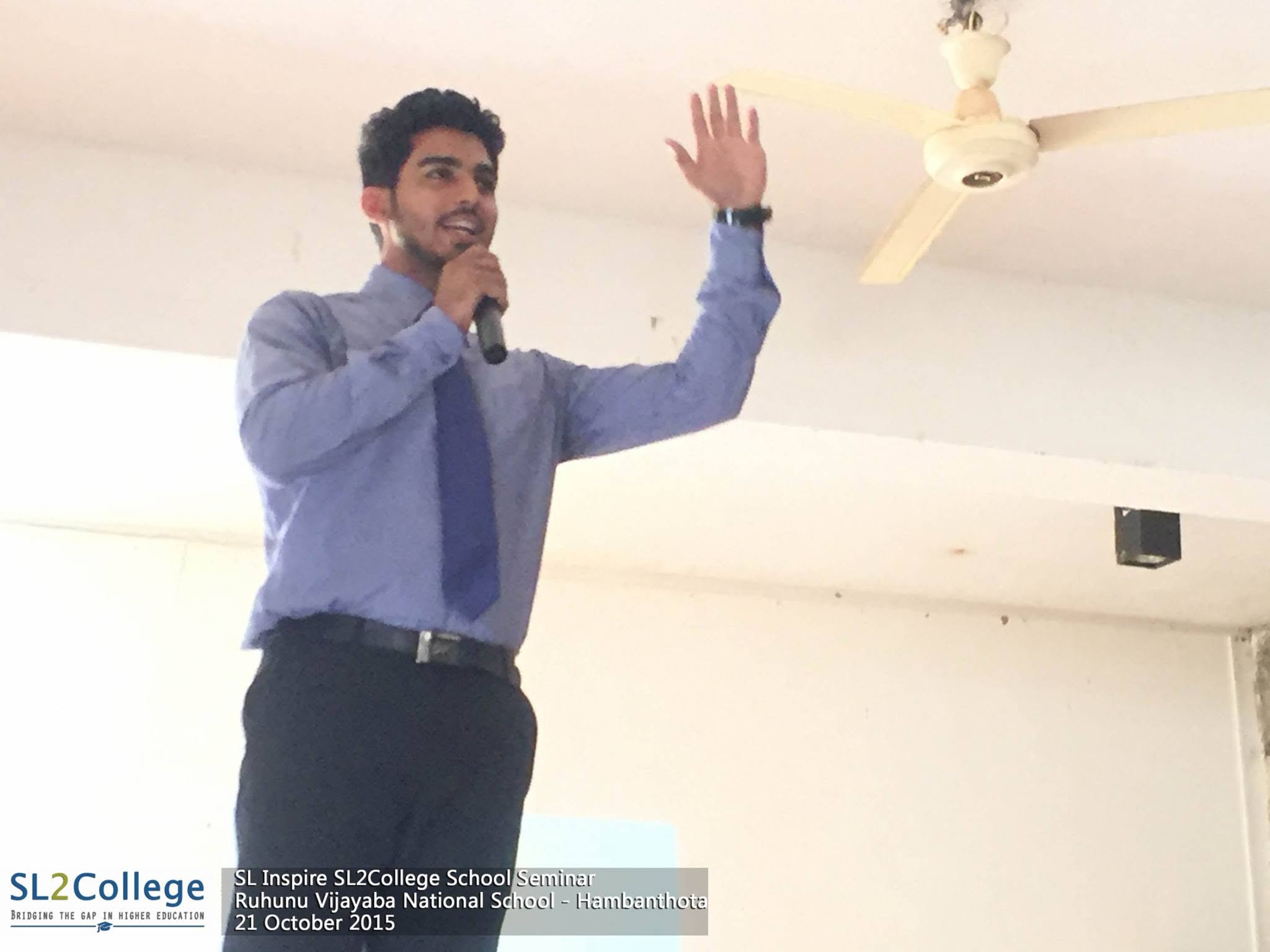 Piumal speaking with a microphone at an SL2College school seminar