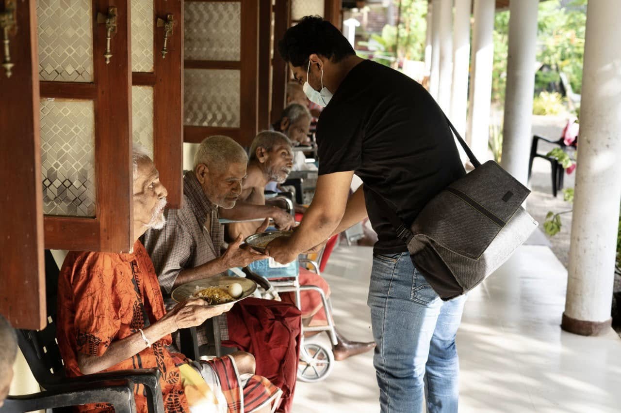 Piumal serving a meal to residents of an elders' home