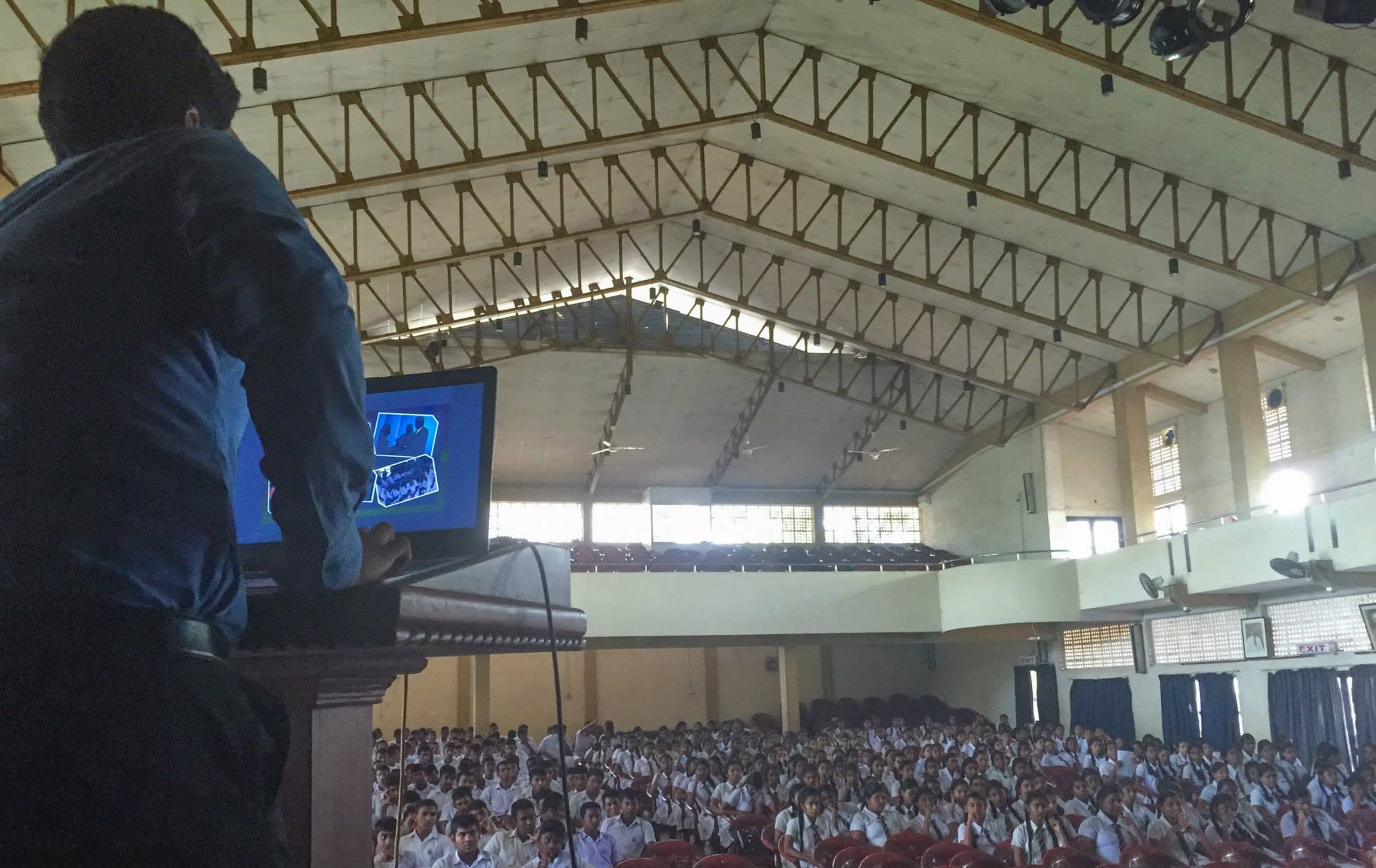 Piumal speaking to a large audience of students in a school hall